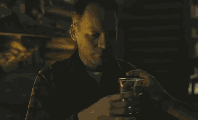 a man in a plaid shirt is holding a glass of wine in his hand .