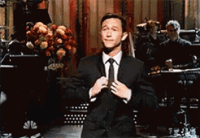 a man in a suit and tie is adjusting his tie on stage