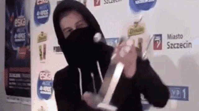 a man in a black hooded sweatshirt is holding a trophy .