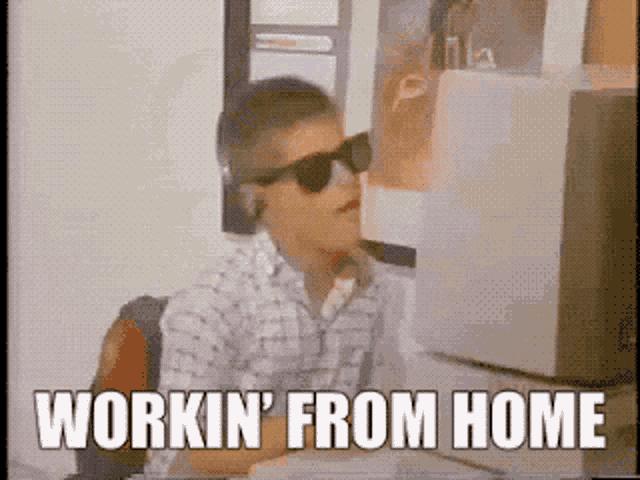 a man wearing sunglasses is sitting at a desk and says workin ' from home