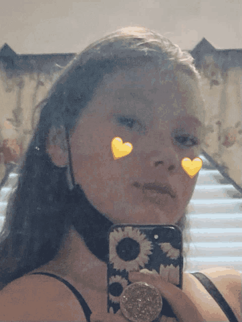 a girl is taking a selfie with a sunflower case on her phone