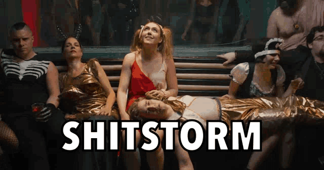 a group of people sitting on a bench with the word shitstorm on the bottom right