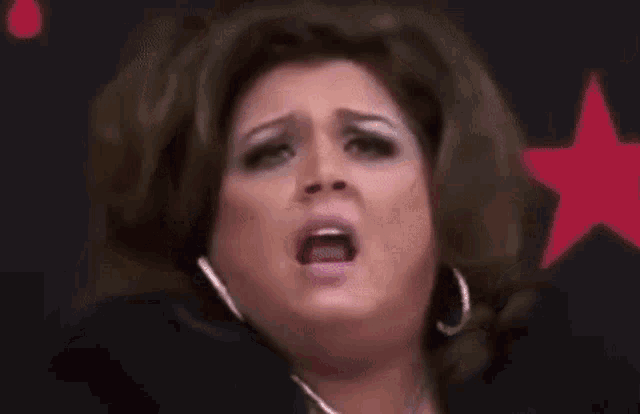 a woman is making a funny face with her mouth open and a surprised look on her face .
