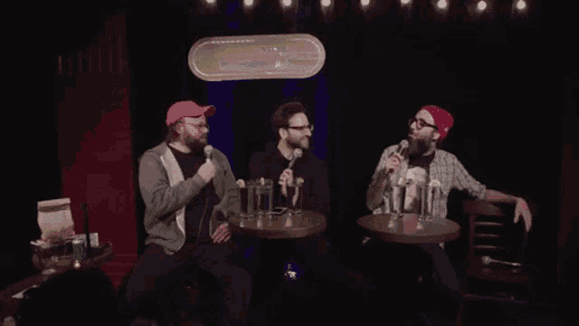 three men are sitting at a table with microphones and a sign that says zooooum !!!
