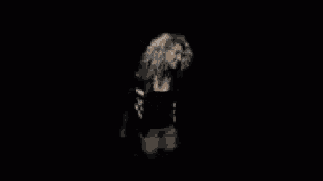 a woman in a black and white striped shirt is standing in the dark .
