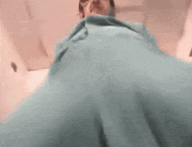 a person is wrapped in a blue blanket and looking down at their feet .