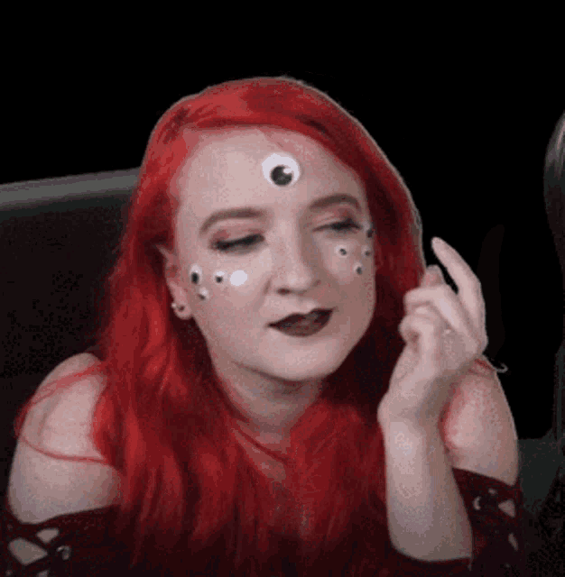 a woman with red hair has googly eyes on her face .