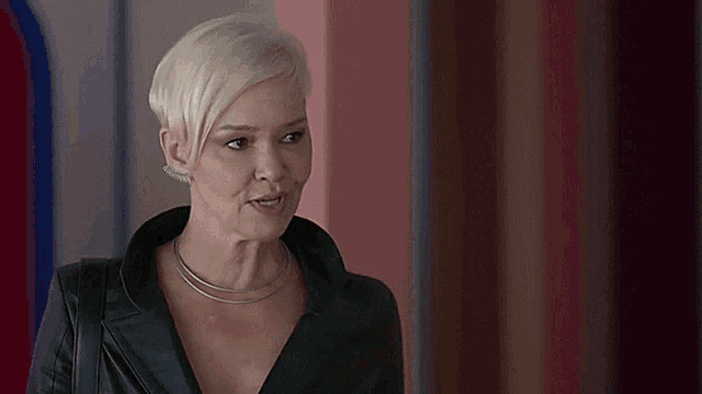 a woman with short blonde hair is wearing a black leather jacket