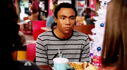 a man in a striped shirt sits at a table in front of a nbc logo