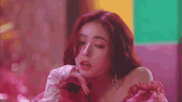 a woman with red hair is wearing a pink dress and heart earrings