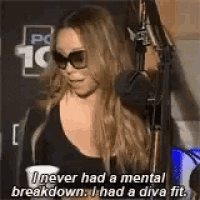 mariah carey is wearing sunglasses and talking into a microphone while standing in front of a microphone .
