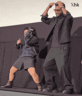 a man and a woman are dancing on a stage with xhk written on the bottom right