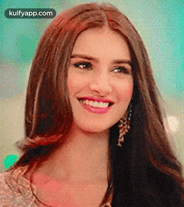 a close up of a woman 's face with long hair and earrings smiling .