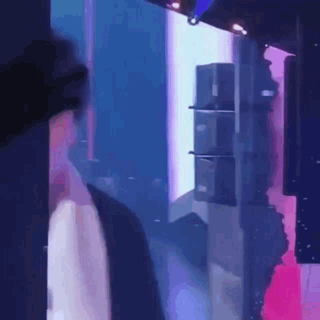 a man is standing in a dark room with purple lights .