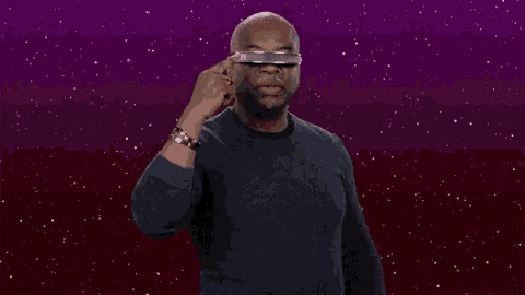 a man wearing a pair of futuristic glasses is pointing at the camera .