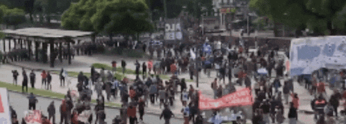 a large crowd of people are gathered in a park with a sign that says " alianza "