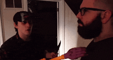 a man with glasses and a beard is holding a knife in his hand