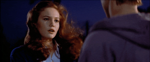 a woman with red hair is talking to a man in a purple jacket