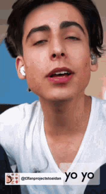 a young man with his eyes closed is wearing ear buds and a white shirt ..