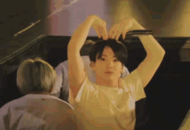 a young man is making a heart shape with his hands .