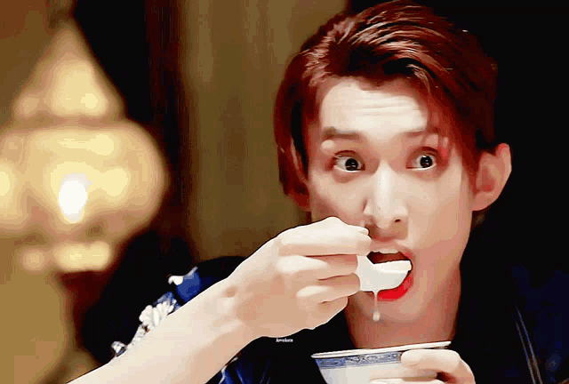 a man with red hair is eating something with a spoon from a bowl