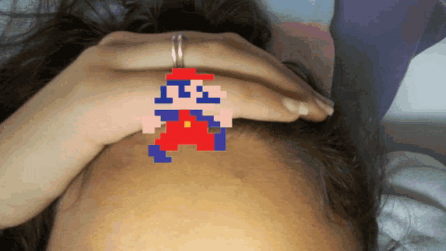 a woman 's forehead has a mario pixel art sticker on it