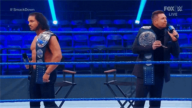 two wrestlers are standing in a ring with a fox live advertisement behind them