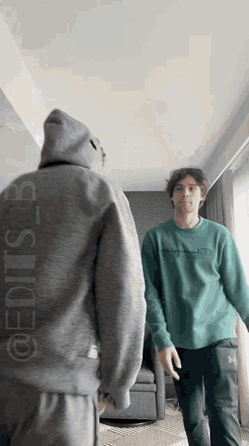 a man in a green sweatshirt is standing next to another man in a grey hoodie