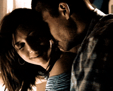 a man and woman are kissing in a dark room and the woman has a ring on her finger