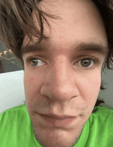 a close up of a man 's face in a green shirt