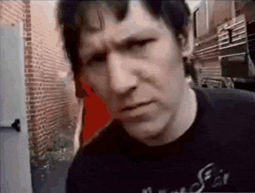 a man in a black shirt with the word fair on it looks at the camera