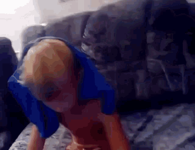 a young boy is laying on a couch with a blue bag on his head .