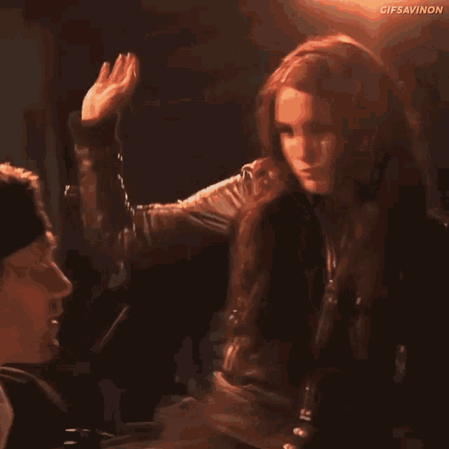 a man and a woman are standing next to each other in a dark room and the woman is giving the man a high five .