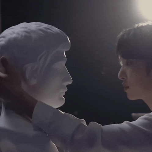 a man holds a statue of a man 's head in his hands