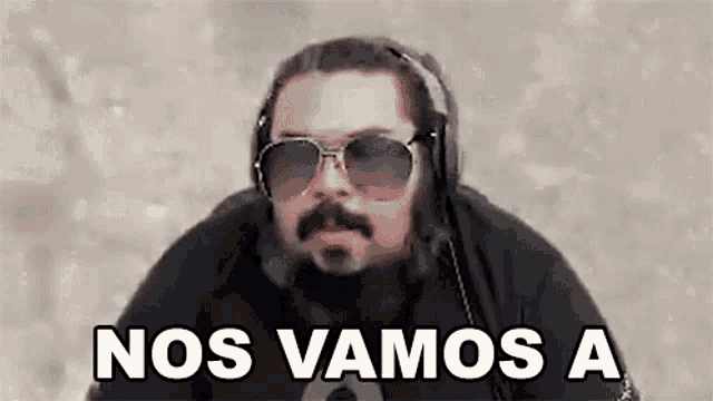 a man wearing headphones and sunglasses is making a funny face and says `` nos vamos a '' .