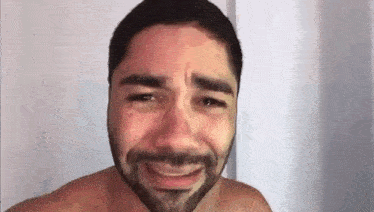 a shirtless man with a beard is crying while looking at the camera .