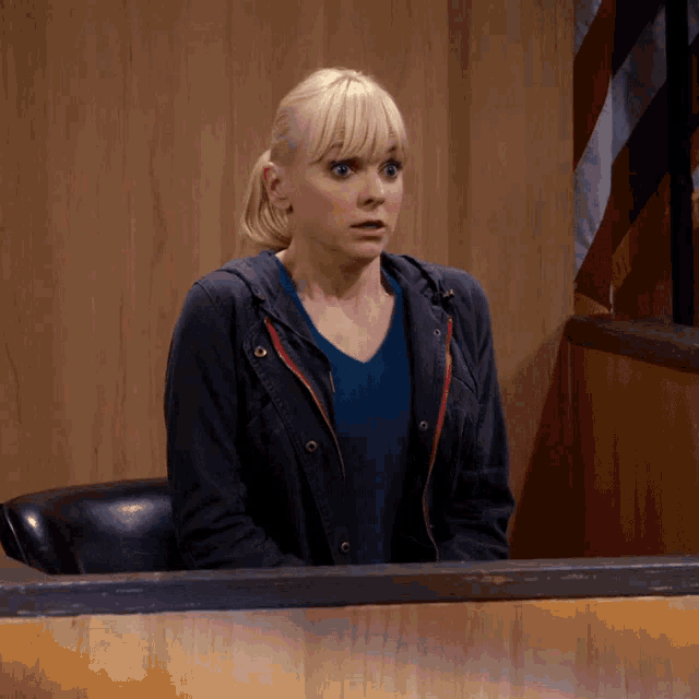 a woman in a blue jacket is sitting at a desk