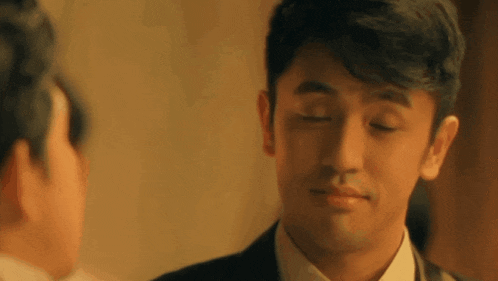 a man in a suit and tie is looking at another man 's face .