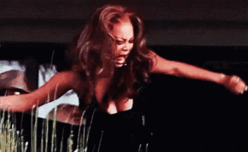 a woman in a black dress is dancing in front of a man in sunglasses .