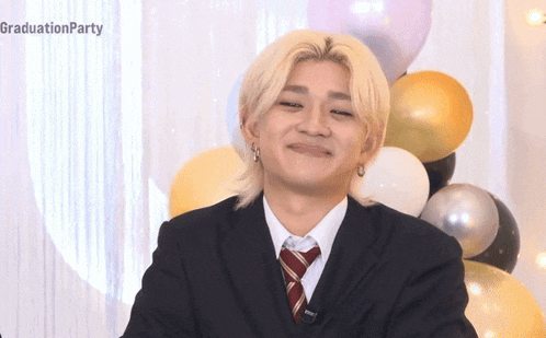 a man wearing a suit and tie is smiling in front of balloons and the words graduationparty