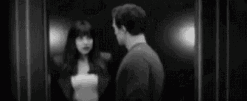 a black and white photo of a man and a woman kissing .