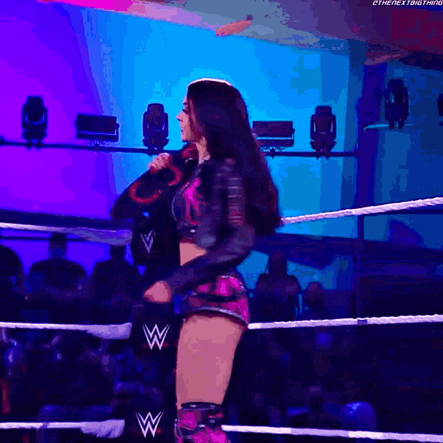 a woman is standing in a wrestling ring with the letters w on her shorts