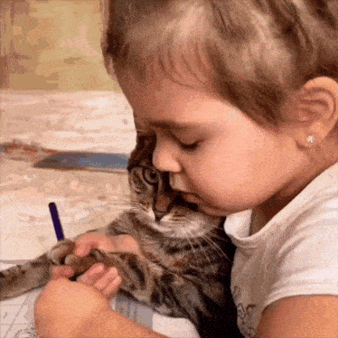 a little girl petting a cat while holding a pencil