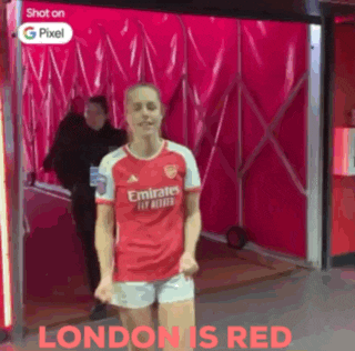 a woman in a red emirates jersey and shorts is dancing