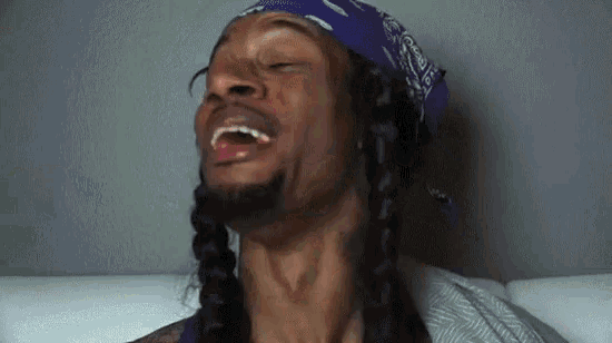 snoop dogg is wearing a purple bandana and laughing .