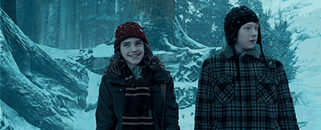 a boy and a girl are walking through the snow