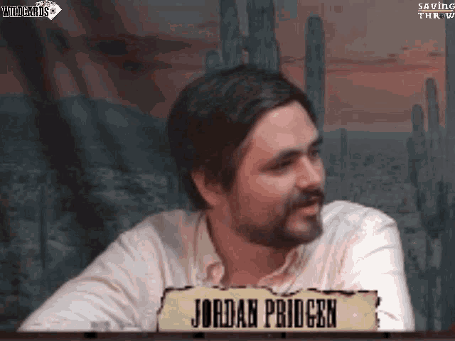 a man with a beard is sitting at a table with a sign that says jordan pridgeen