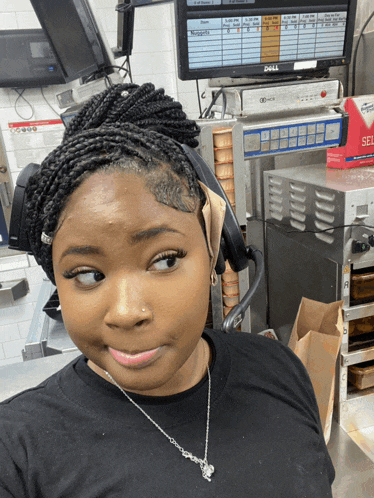 a woman wearing headphones stands in front of a dell computer