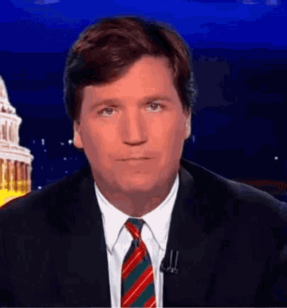 a man wearing a suit and tie is looking at the camera