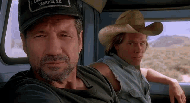 a man wearing a yankton s.d. hat sits next to another man